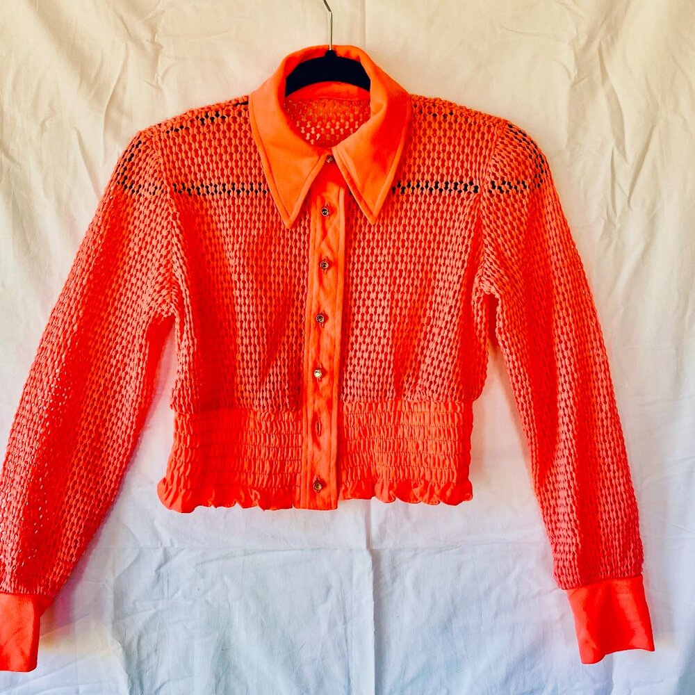 Hot pink fishnet-style cropped sweater jacket.